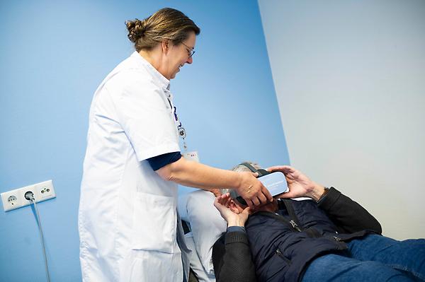 Verpleegkundig specialist helpt patiënt op Pijnpoli met VR-bril
