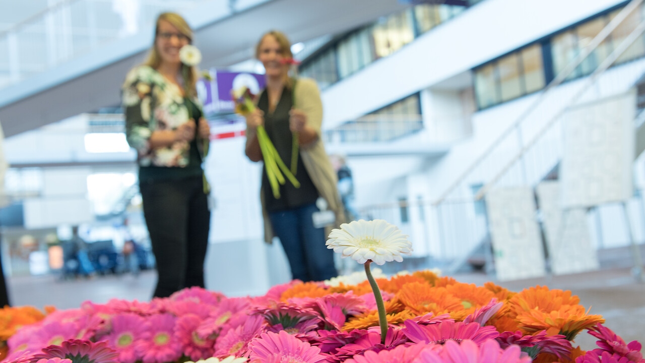 2 collegas delen bloemetjes uit