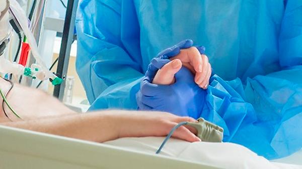 IC-verpleegkundige houdt hand IC-patiënt vast