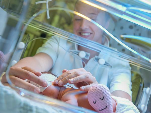 Verpleegkundige verzorgt baby in couveuse
